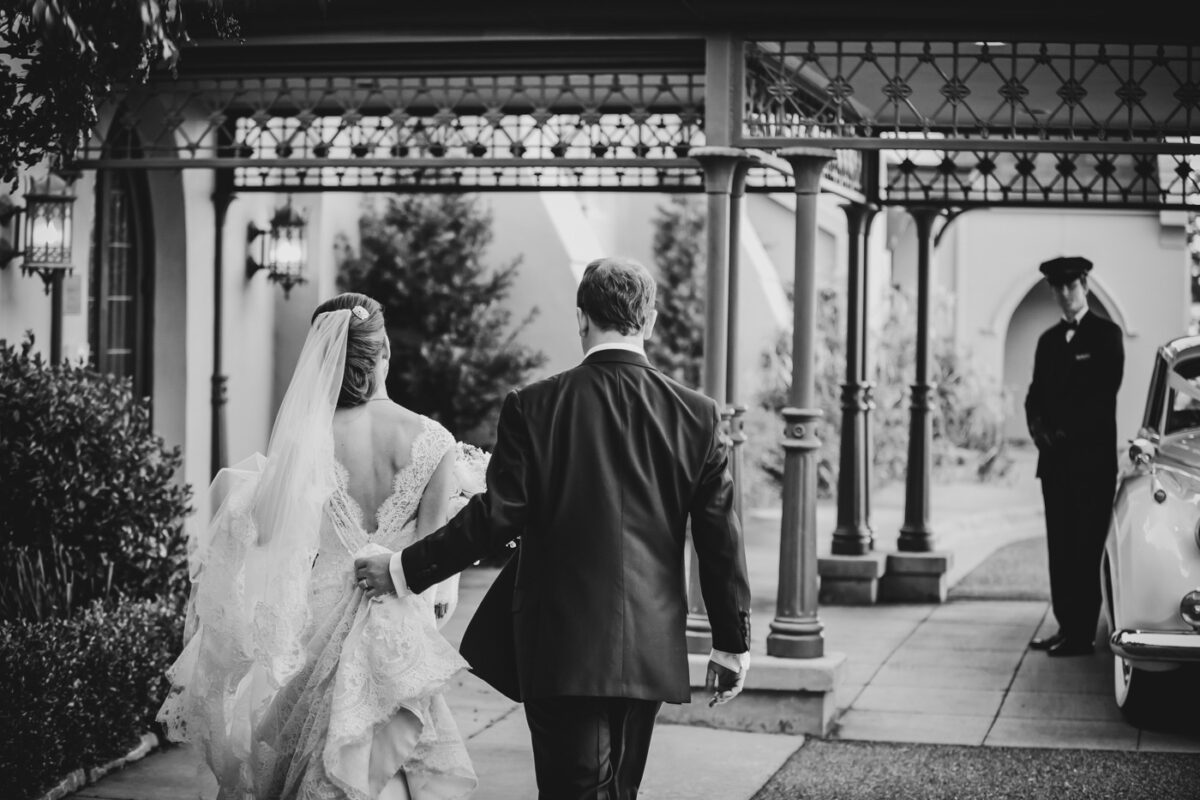 A bride and groom walking to their awaiting chauffeur and Rolls-Royce.