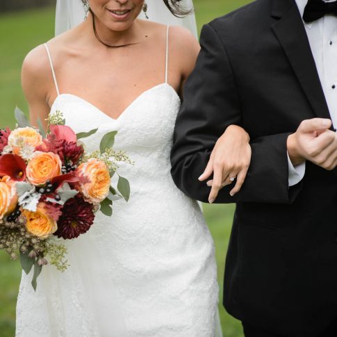 A quick detail shot showcasing the warm summery floral arrangement and the pristine white lace of the wedding gown.